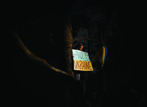Una joven sostiene un cartel en la oscuridad contra la invasión de Ucrania. © Jakub Ivanov